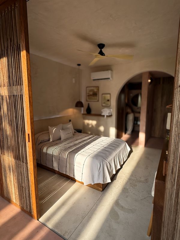 Bed glimpsed through the arched divider, light streaming in