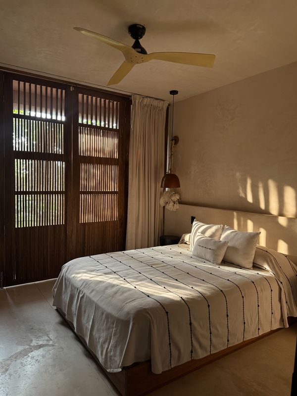 Bed framed by timber screen doors at golden hour